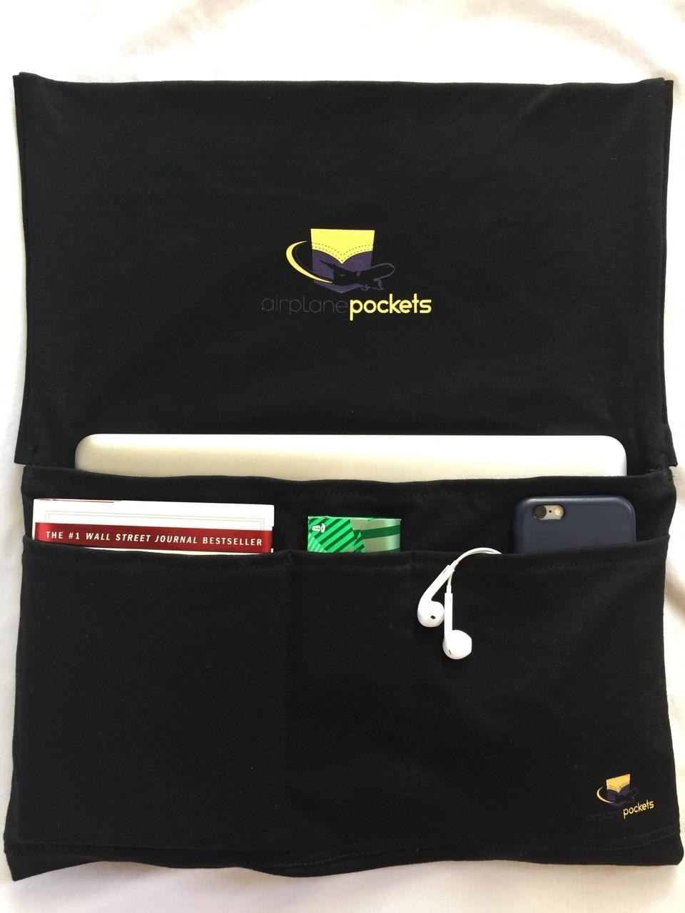 Reviewer&#x27;s photo of the Airplane Pockets seatback organizer in use, holding a tablet, a book, some gum, a phone, and some earbuds