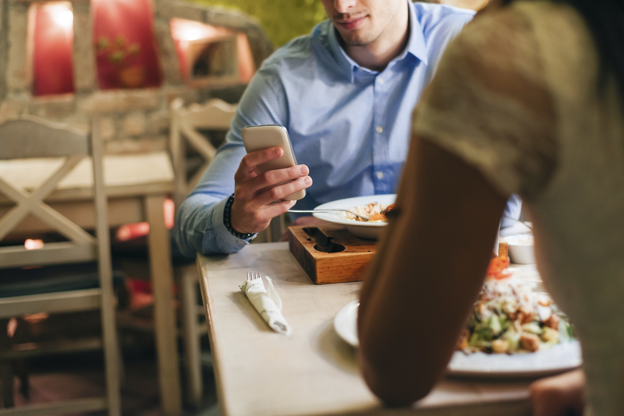 person on their phone during dinner