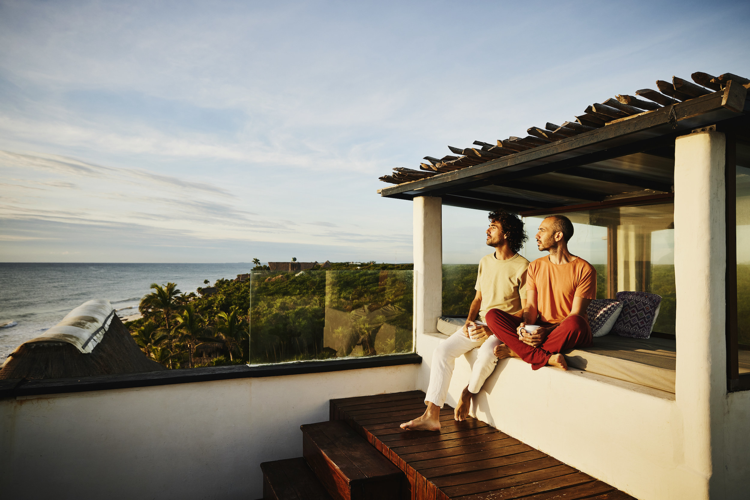 Two men sitting on a patio overlooking the ocean