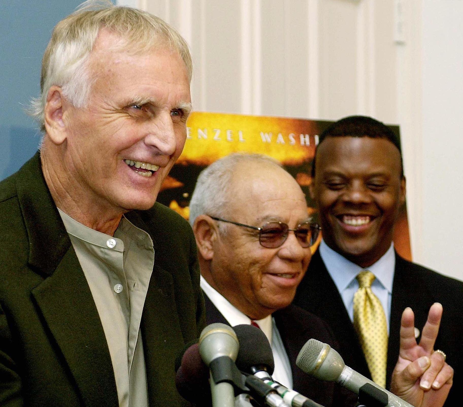 US Rep JC Watts Jr looks on as former Alexandria, Virginia, high school football coaches Bill Yoast and Herman Boone discuss the film &quot;Remember the Titans&quot; at a podium