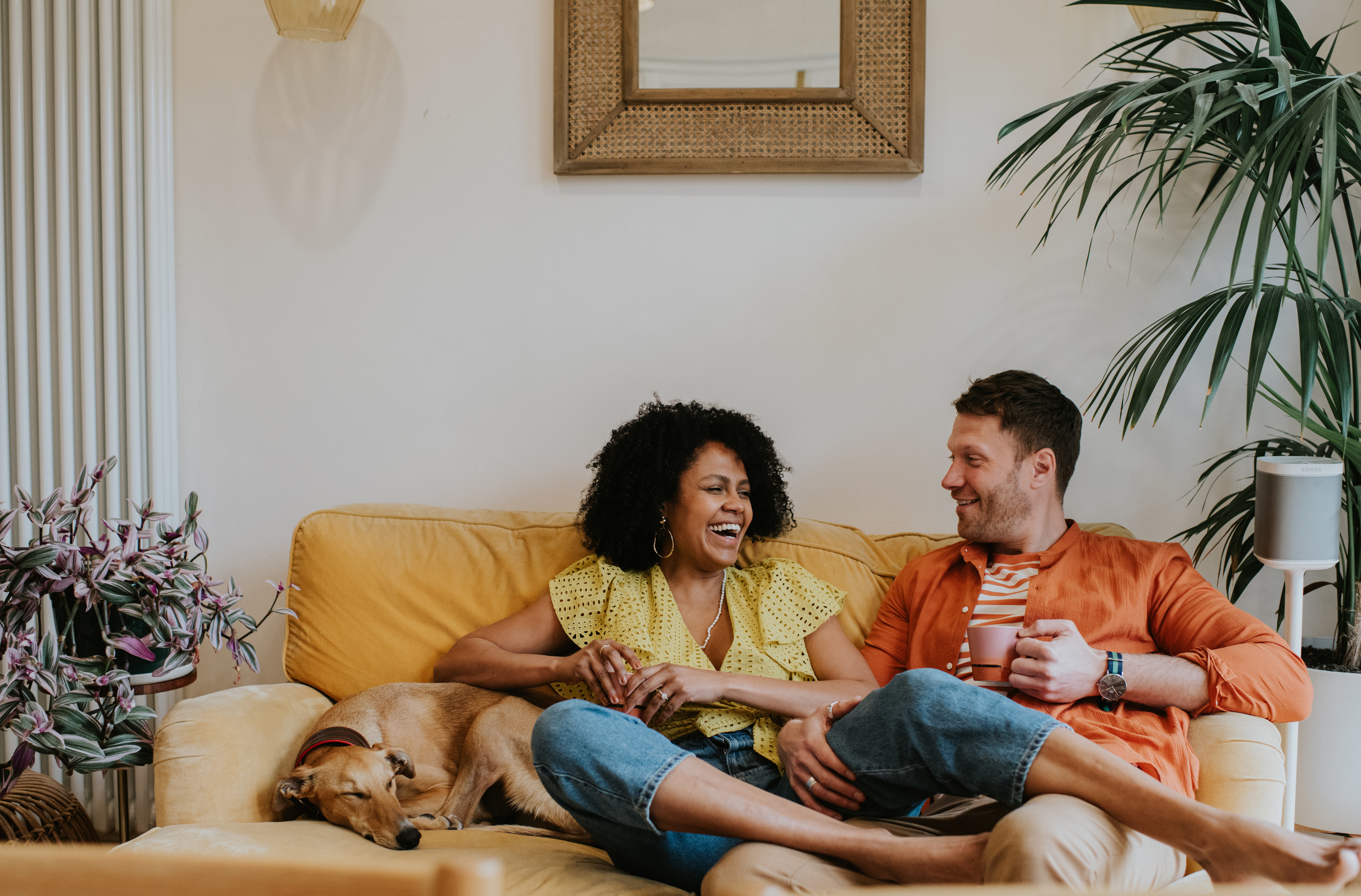 A smiling couple on the couch with their dog