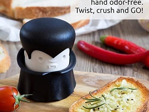 the garlic crusher on a cutting board with a slice of bread beside it