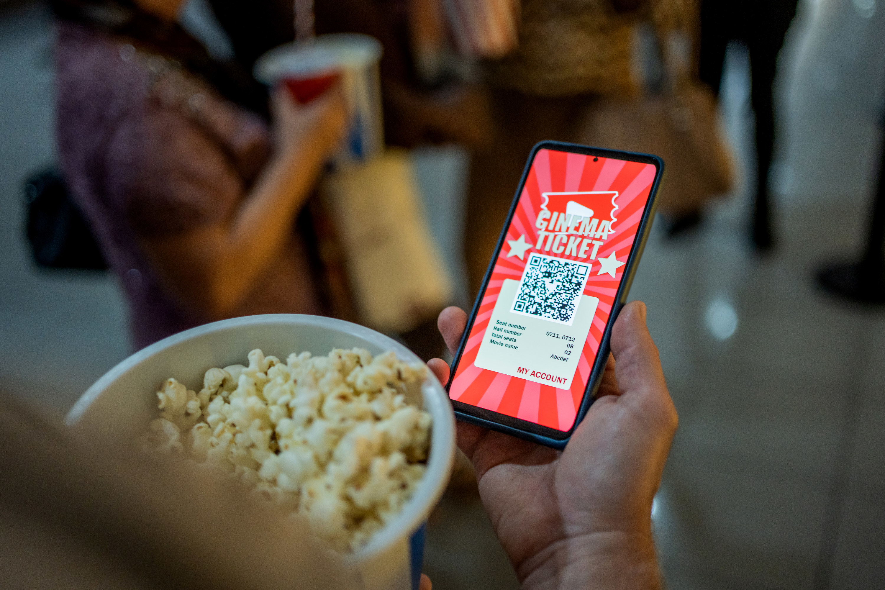 Someone holding popcorn and a digital movie ticket