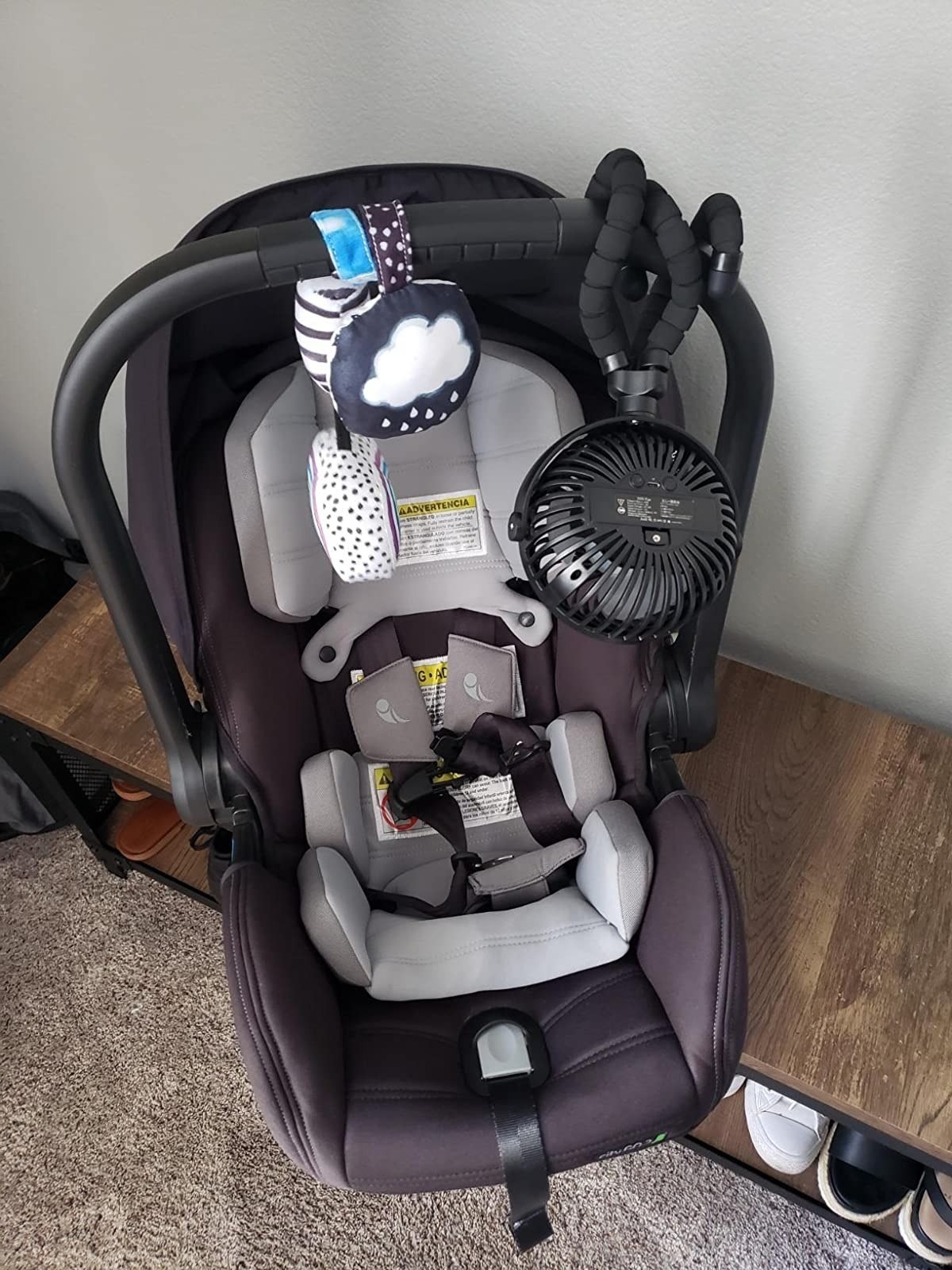 black stroller fan clipped onto handle of black and gray baby carseat