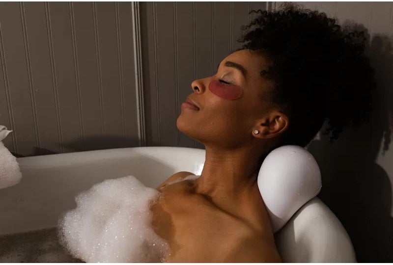 a person resting on a white bath pillow in a white tub