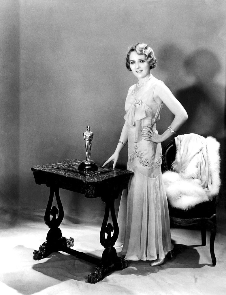 Mary posing by a table with her Oscar