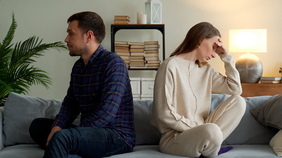 couple sitting with their backs to each other, and the woman looking visibly upset