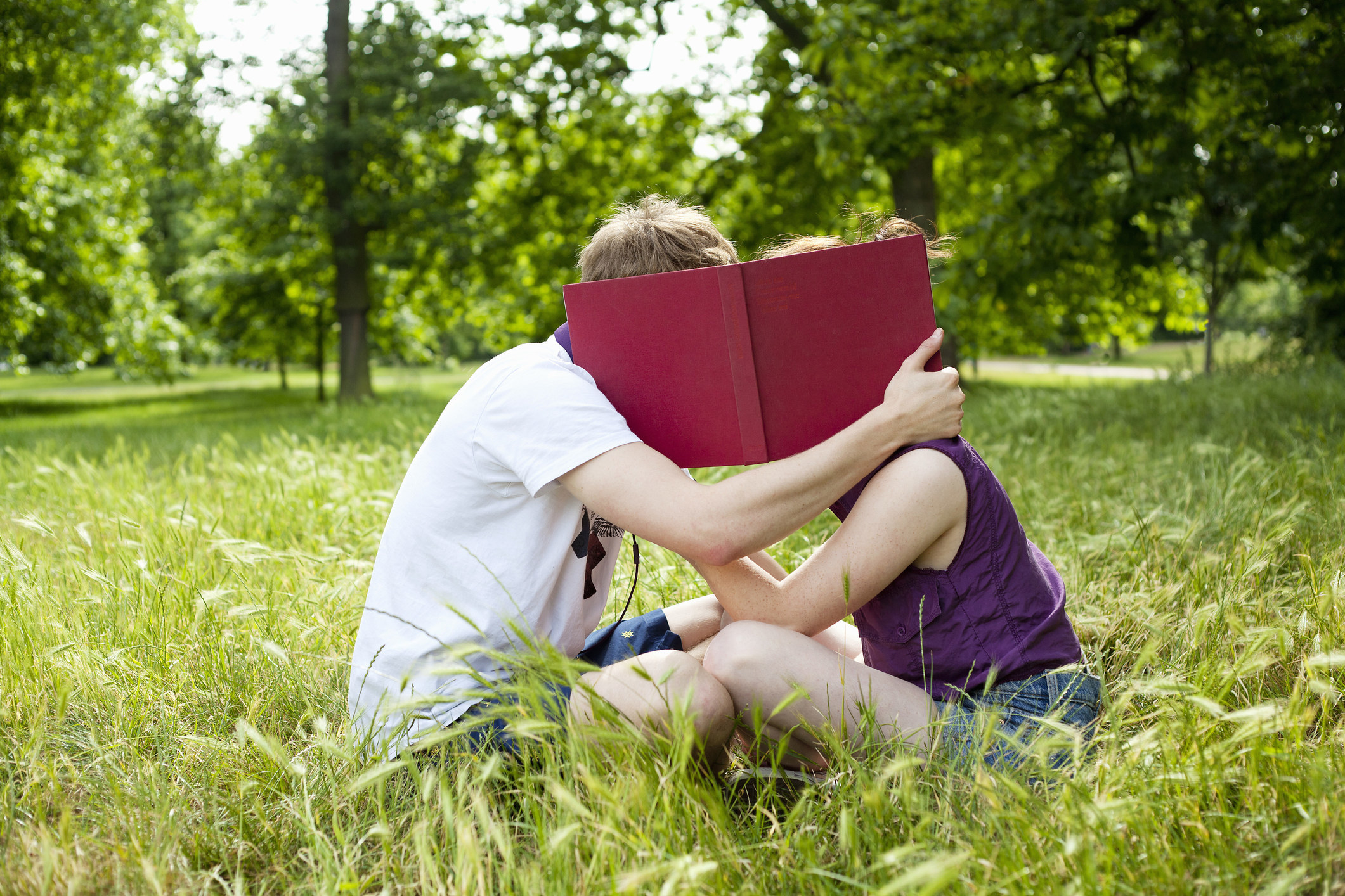 A couple seemingly kissing behind a book