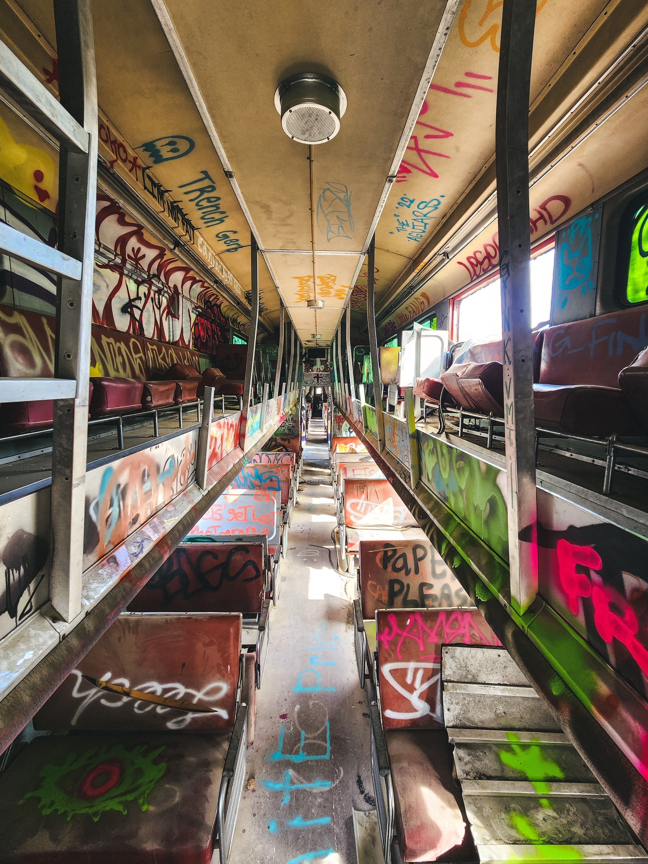 an old train car with graffiti covering the dusty seats and tables