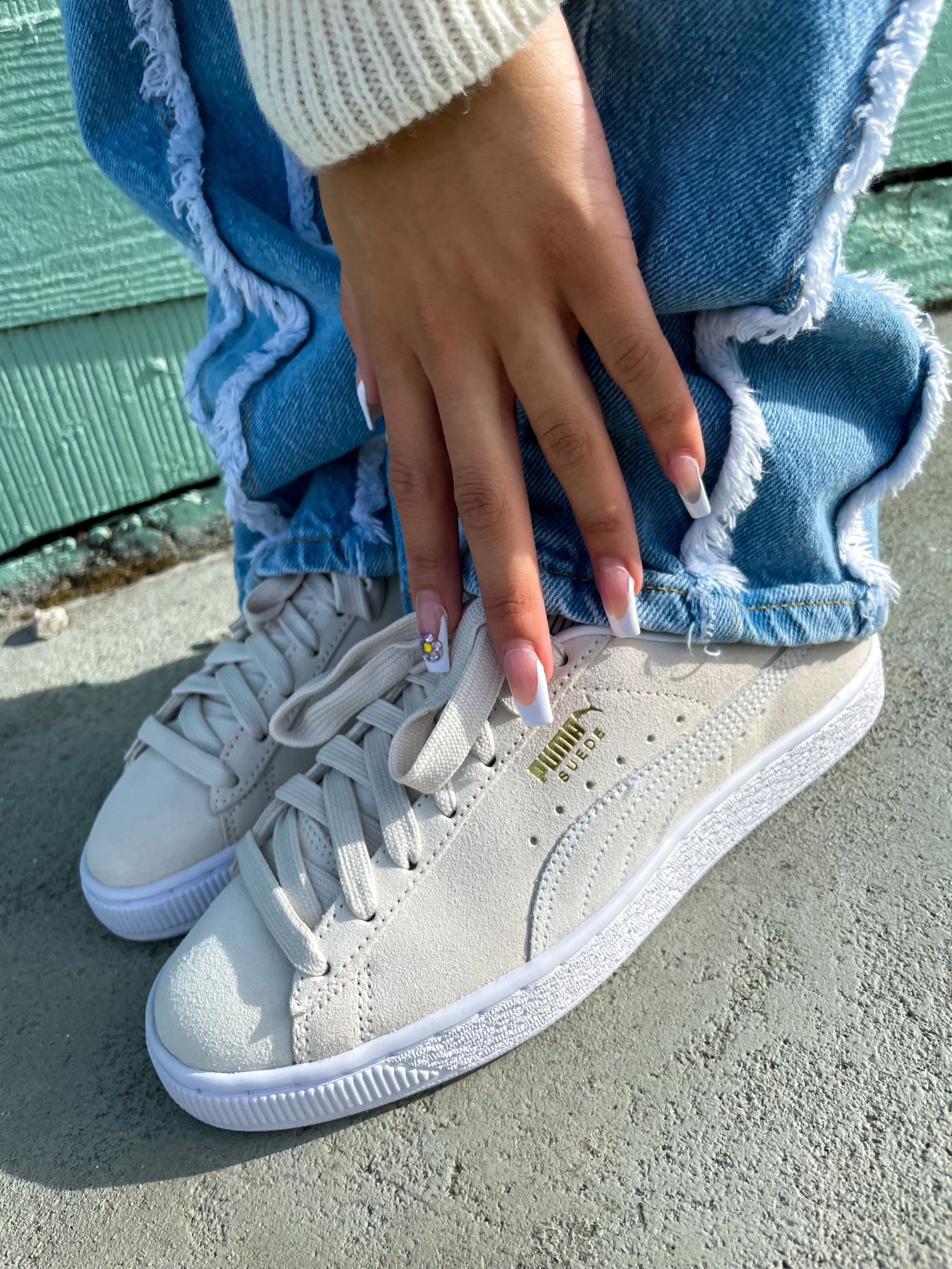 Influencer JasmineCorly&#x27;s hand is posed atop her Puma Suede sneakers