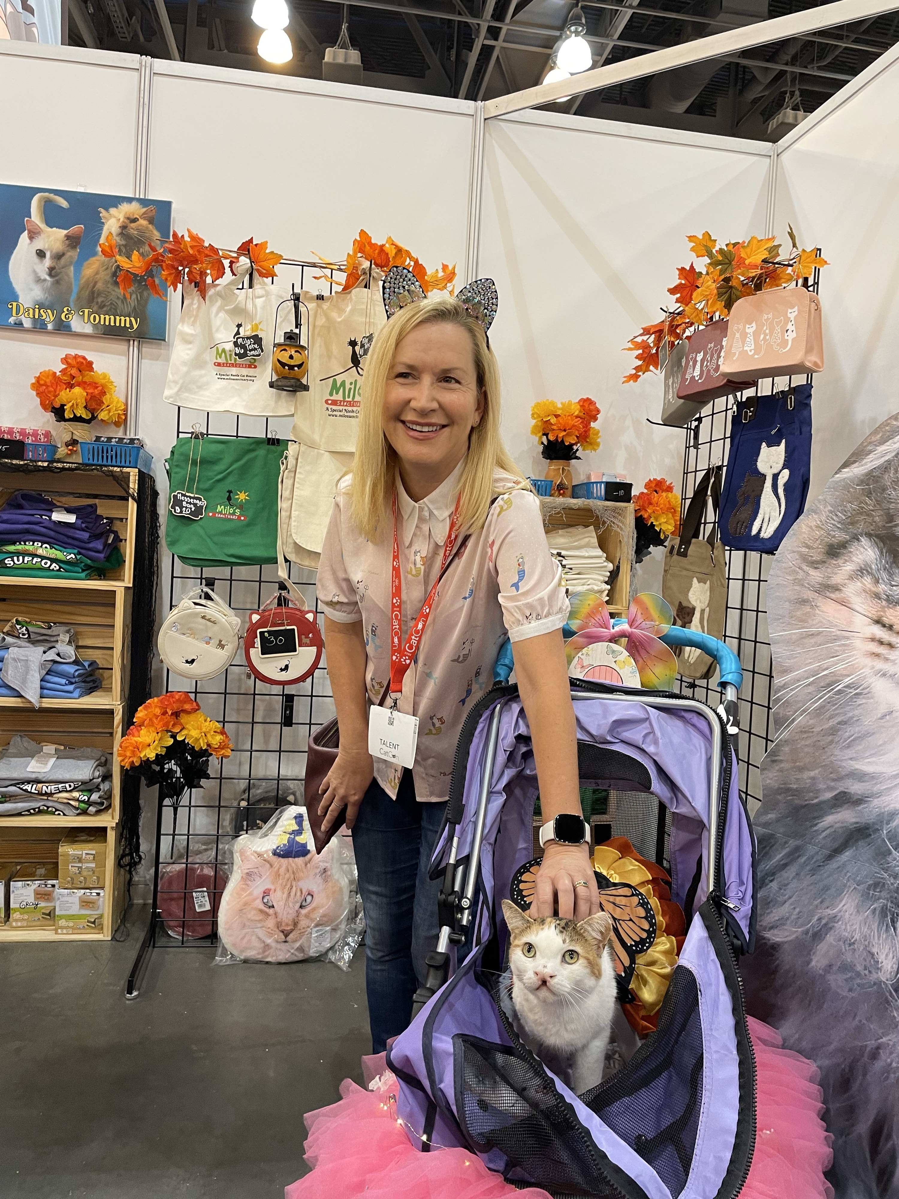 Angela Kinsey pets Snickers who sits in a stroller in front of cat merch