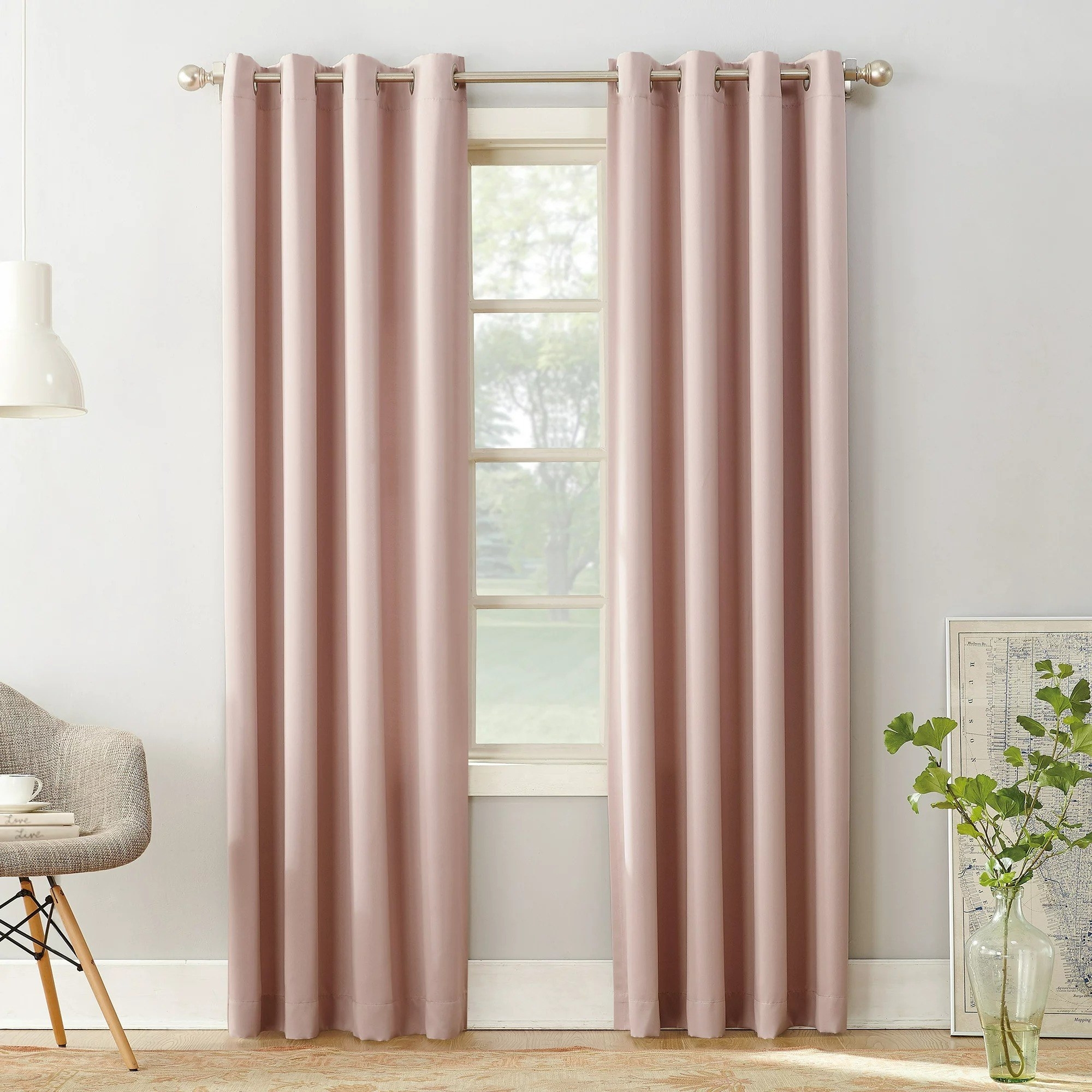 A blush curtain panel on a curtain rod in a room near a window