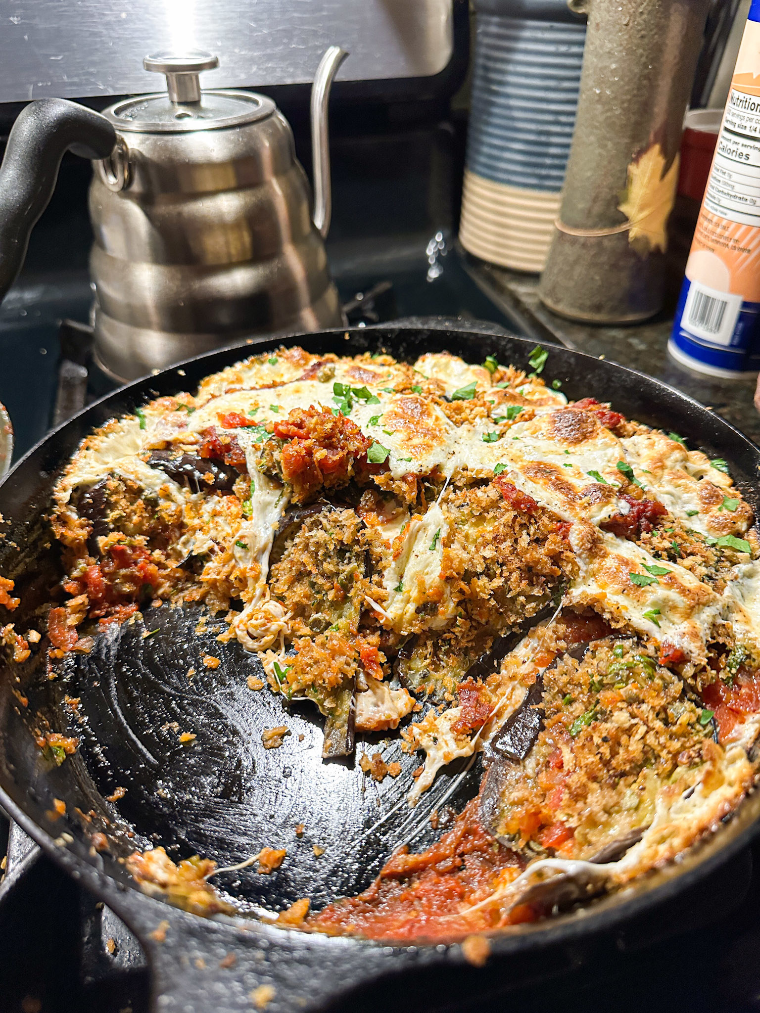 Eggplant Parm in a cast-iron skillet after some has been scooped out