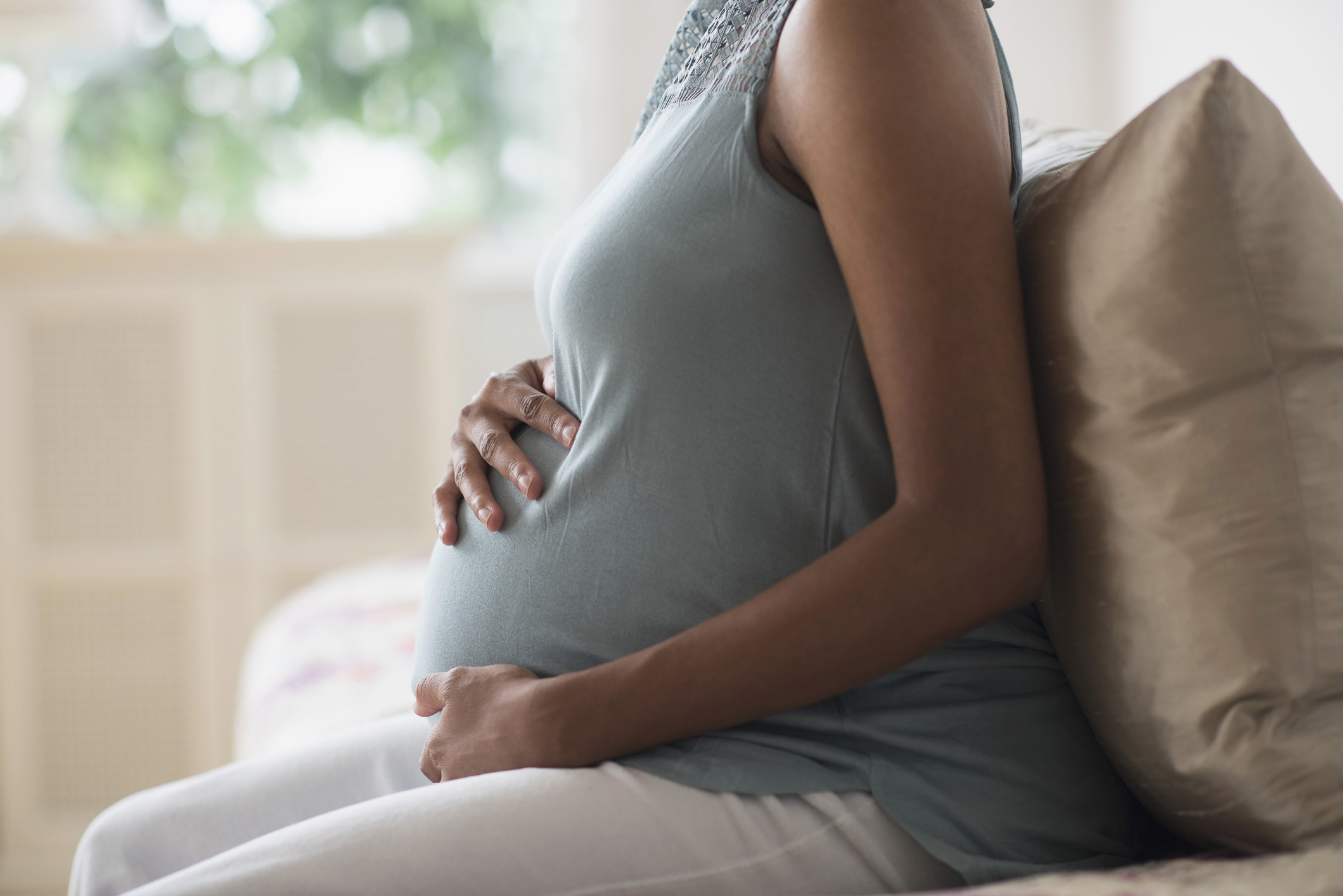 A pregnant woman sits and holds her belly