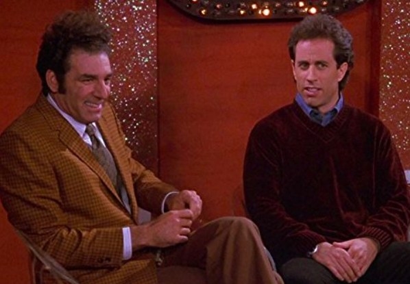 Kramer and Jerry sit on a stage next to each other