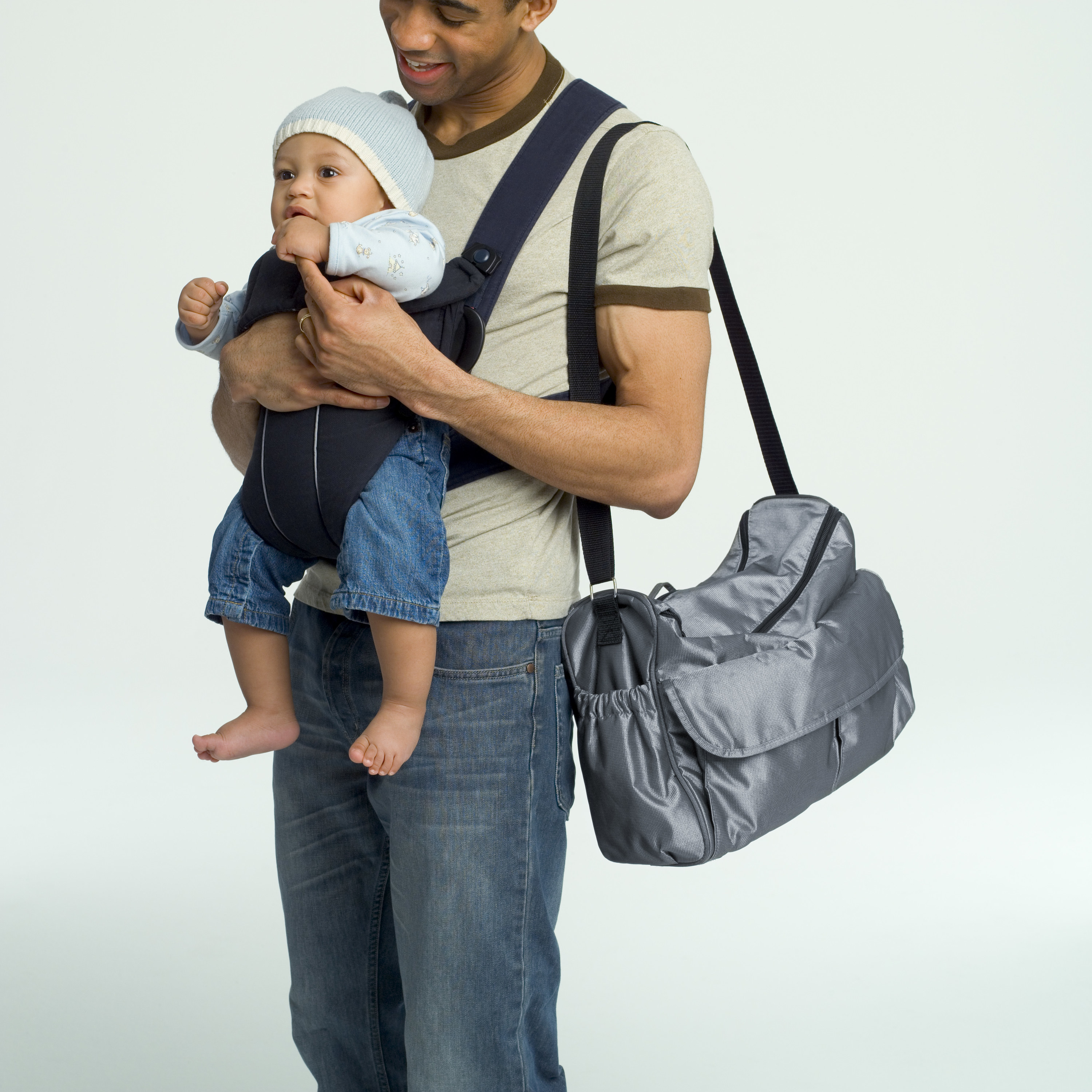 dad holding baby in front carrier with diaper bag slung over shoulder