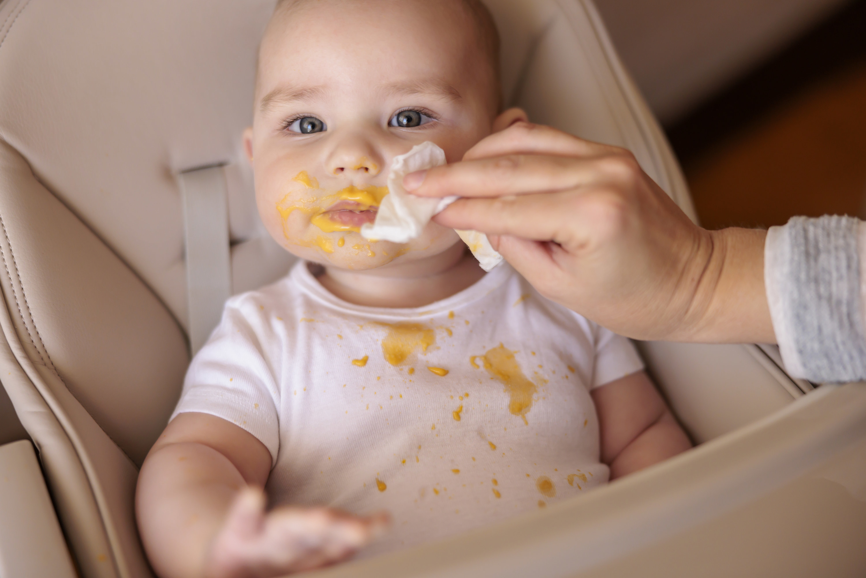 person wiping baby&#x27;s face with a baby wipe during a messy feed