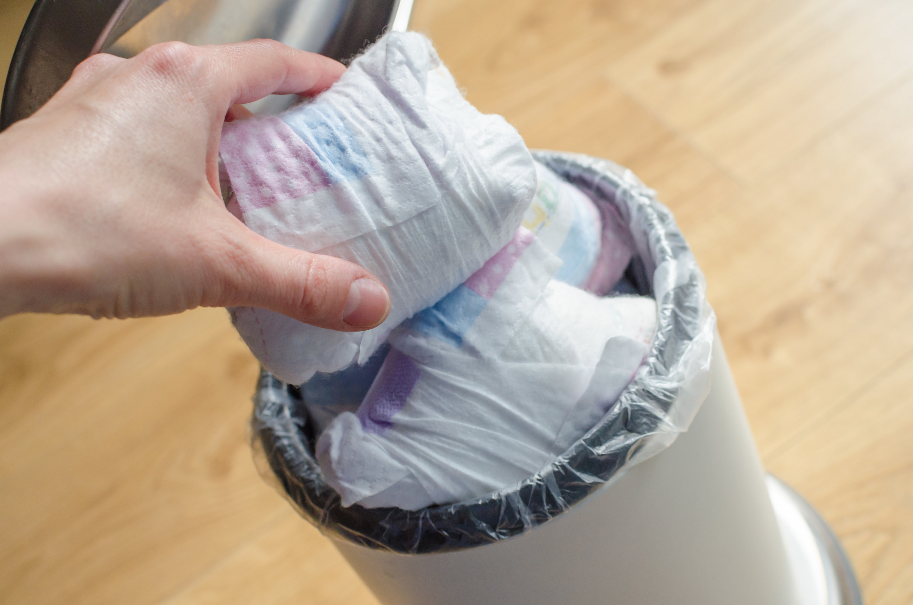 Woman hand put used diaper to the Trash bin full of used diapers