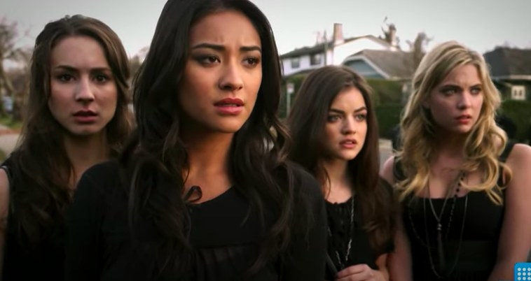 The four leads in Pretty Little Liars stand in a row wearing black and looking worried