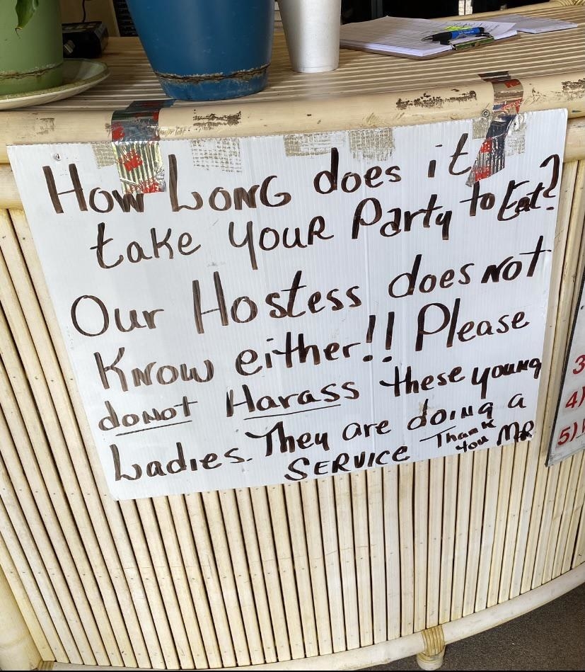 The sign reads &quot;how long does it take your party to eat? Our hostess doesn&#x27;t know either! Please do not harass these young ladies, they are doing a service&quot;