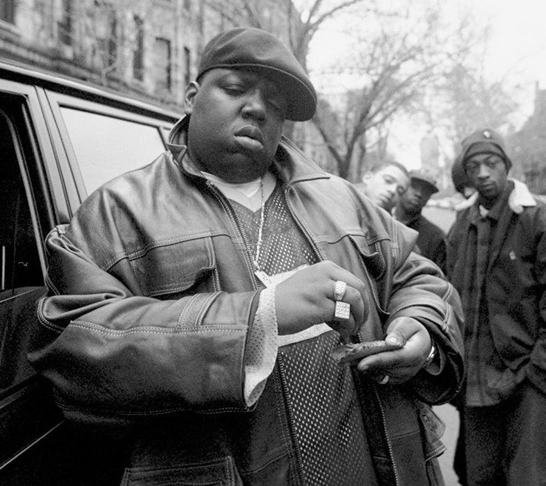Rapper Notorious B.I.G., aka Biggie Smalls, aka Chris Wallace rolls a cigar outside