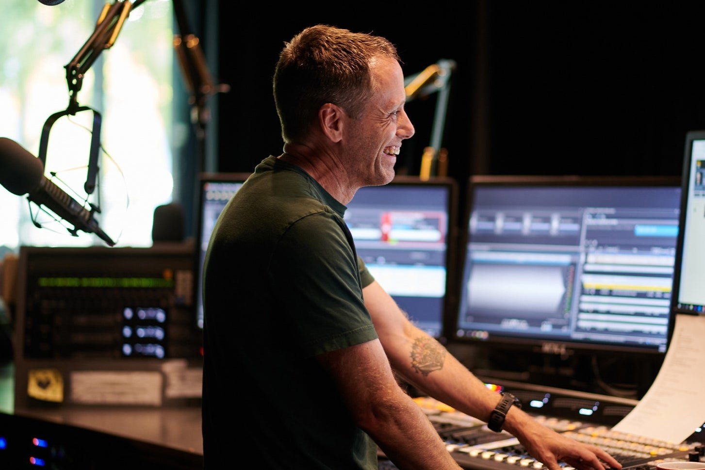 the side profile of a man grinning in a radio booth