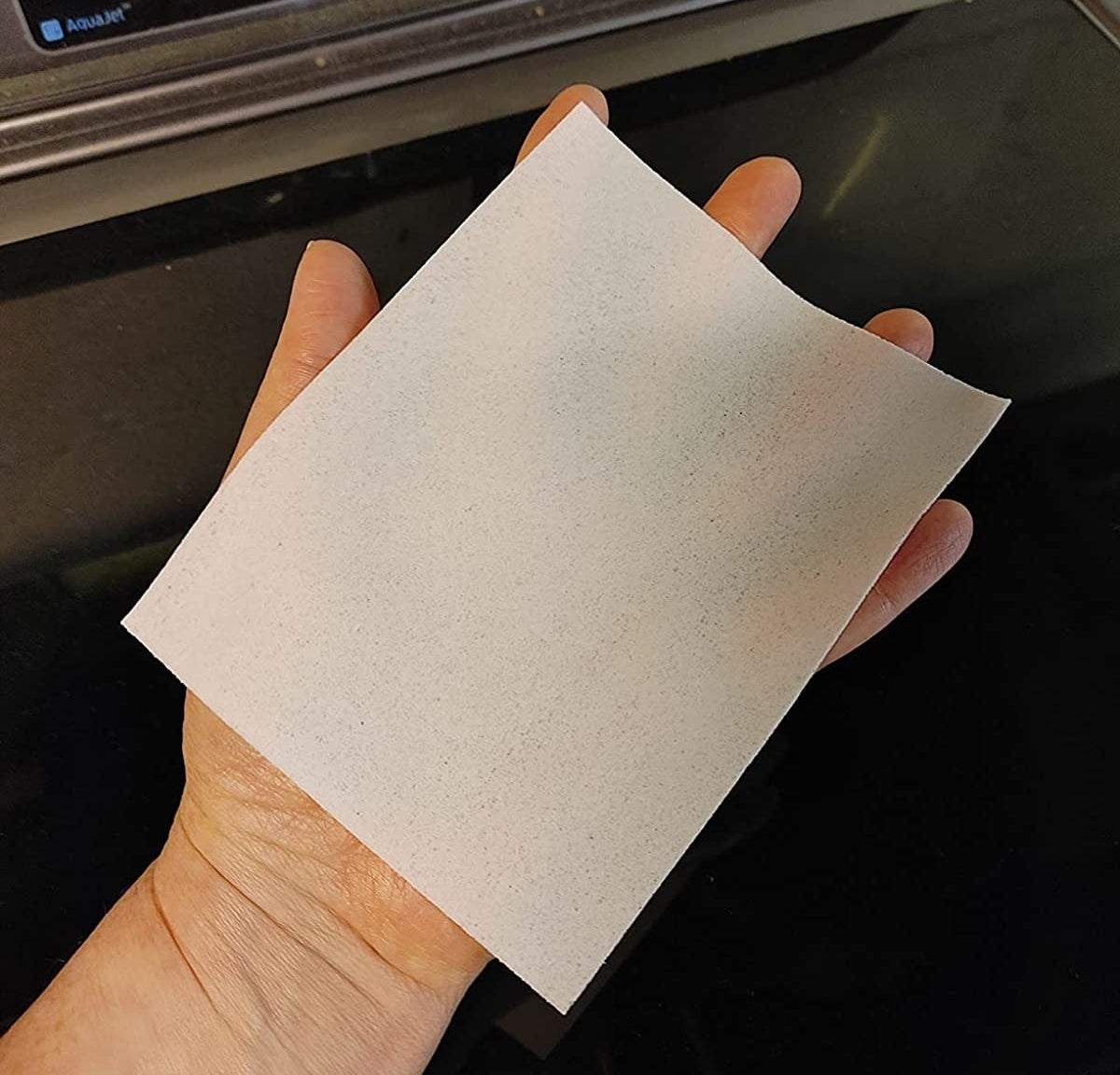 Reviewer&#x27;s photo of a hand holding one of the detergent sheets