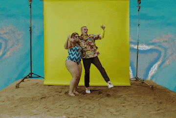 GIF of Bad Bunny hopping and embracing a woman in a swimsuit