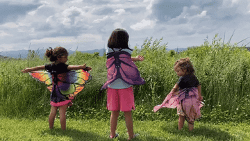 GIF of three children wearing and waving colorful butterfly wings
