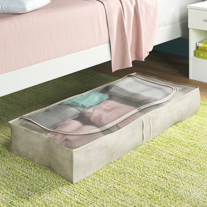 an under-the-bed storage bag holding clothes next to a bed
