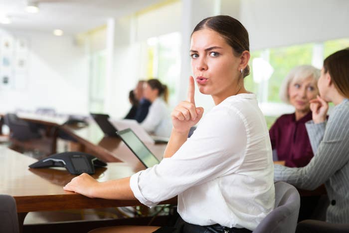 Woman shushing someone in a business meeting