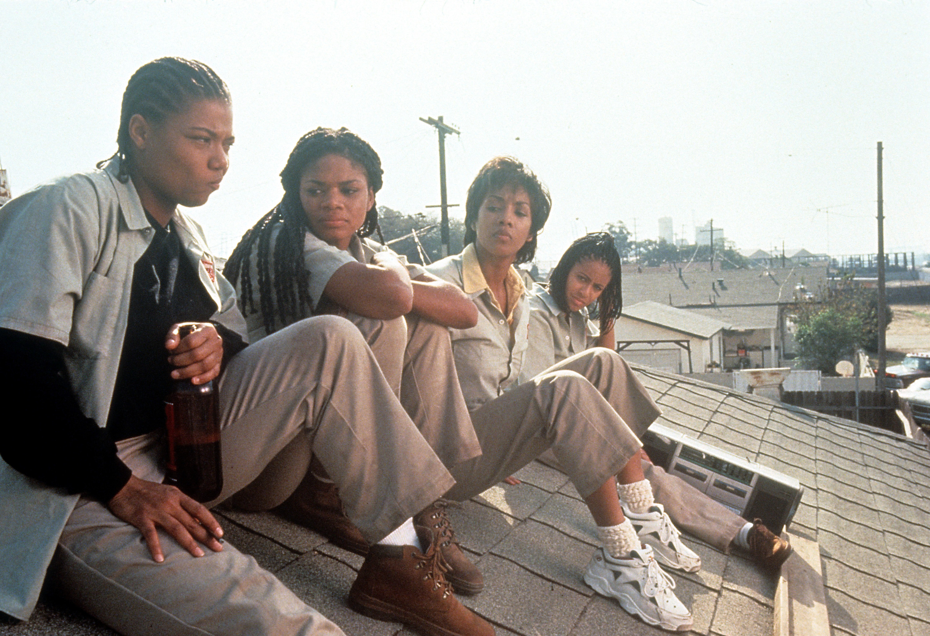 Four Black women sitting on the roof on a house