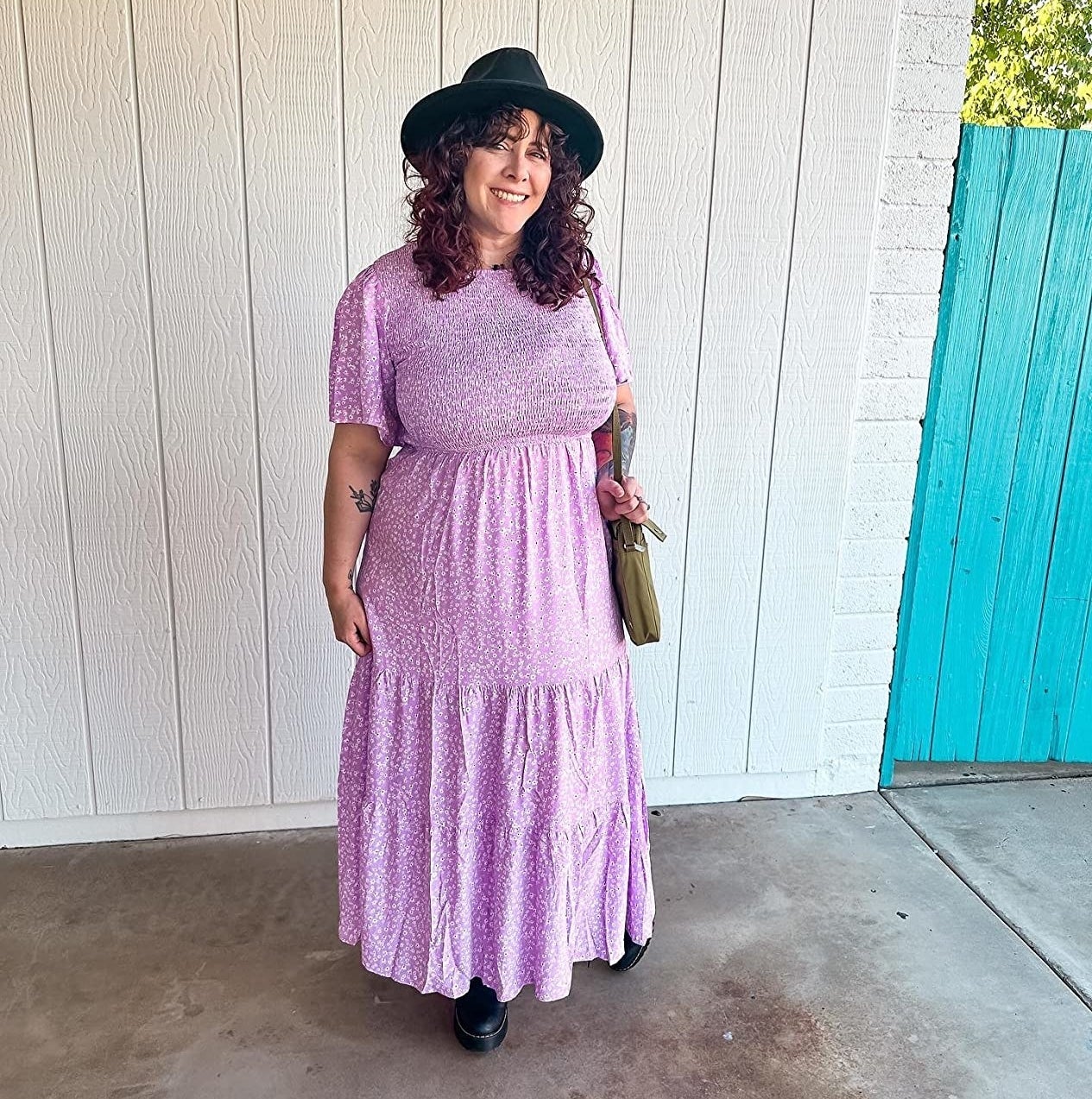 A reviewer in a purple dress with black shoes and black hat