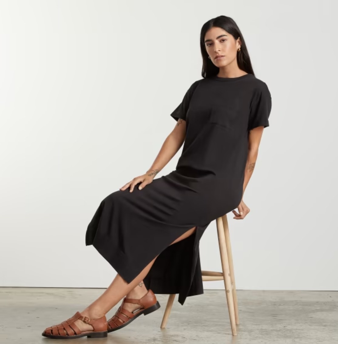 A model wearing a black dress with brown shoes