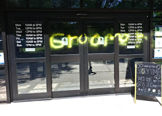 The automatic sliding doors of a library with the word &quot;groomer&quot; spray-painted on them