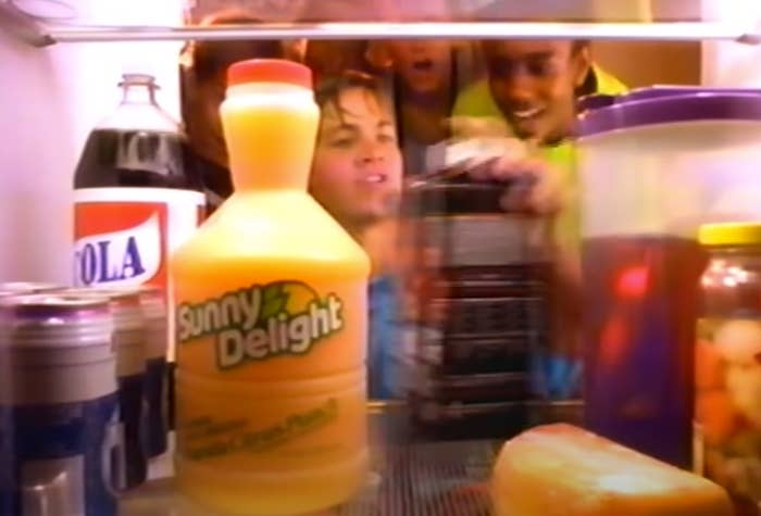 Kids looking into a fridge which has a bottle of Sunny Delight