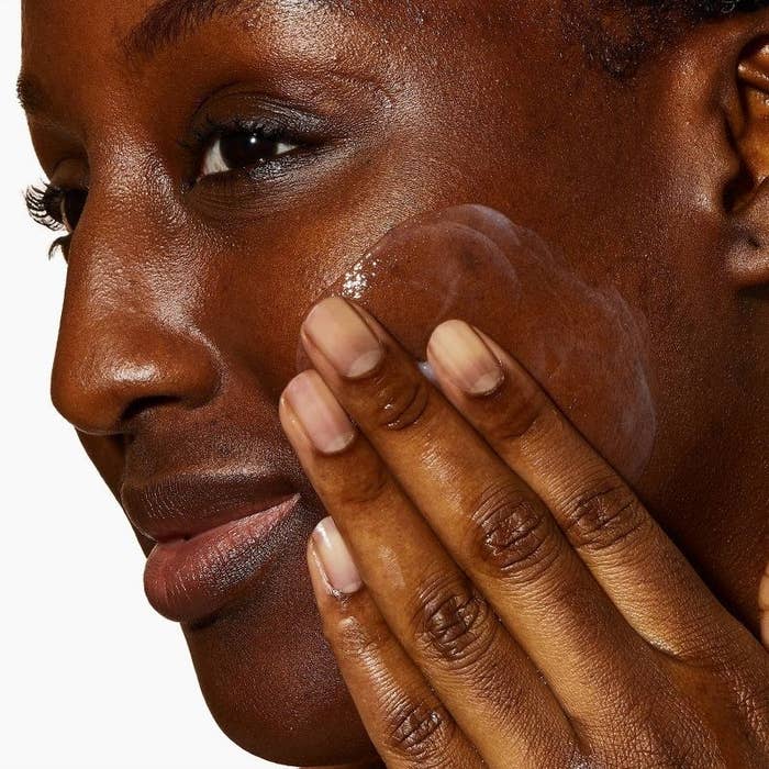 A person applying facial wash to their skin