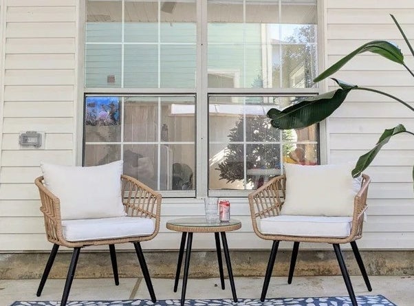 The rattan set with black legs and white cushions on a porch