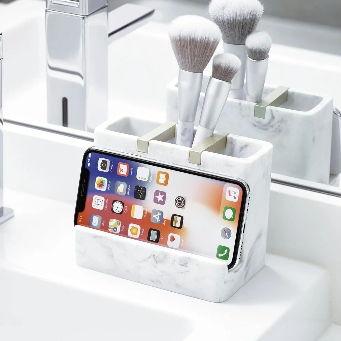The organizer with three compartments and a phone stand holding a phone on the ledge of a sink