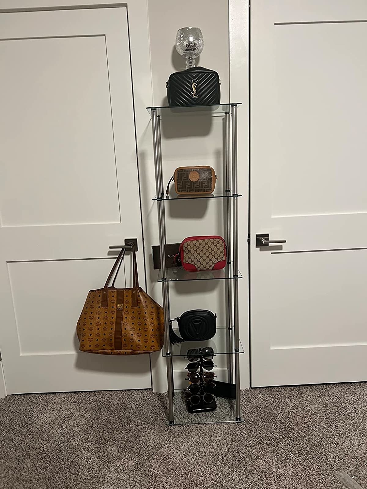 Reviewer&#x27;s glass tower with purses on each shelf and sunglasses on bottom shelf