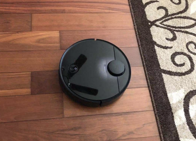 the black robot vacuum on a hardwood floor