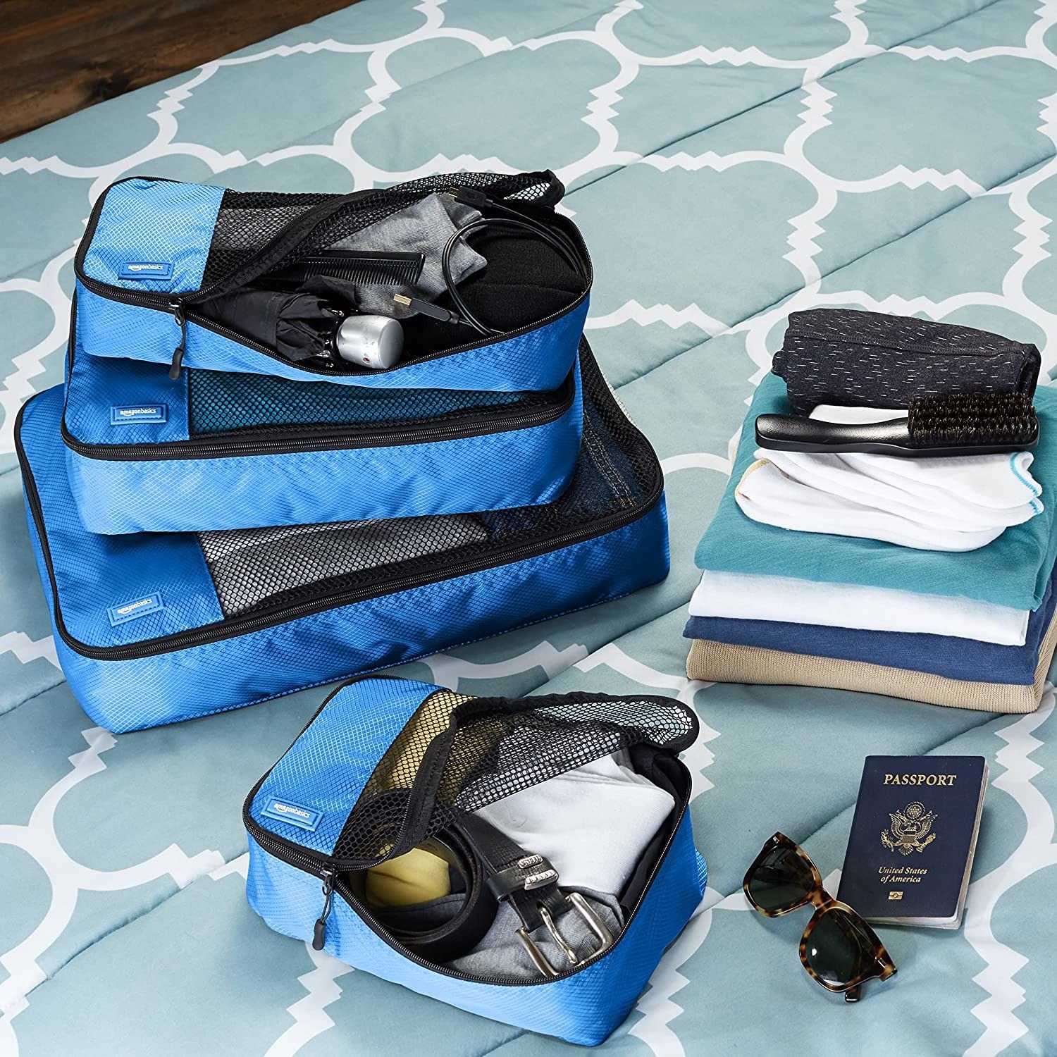 Four filled blue and black packing cubes placed on a bed