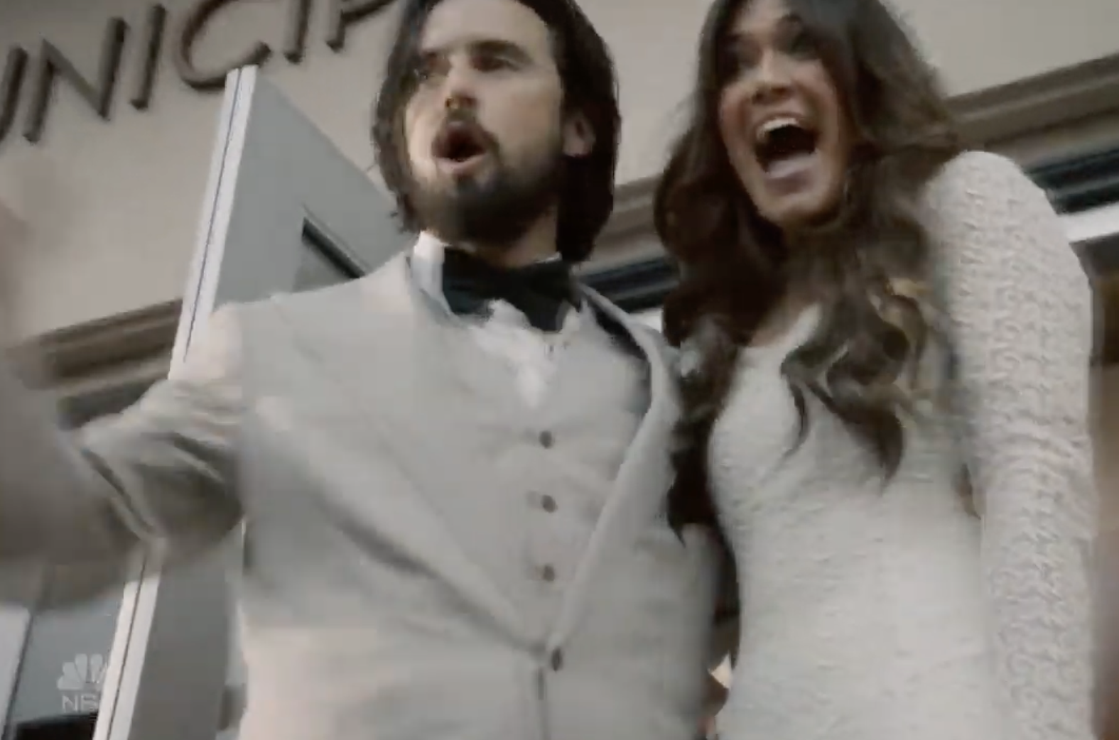 Jake and Rebecca stand outside the courthouse wearing white and cheering