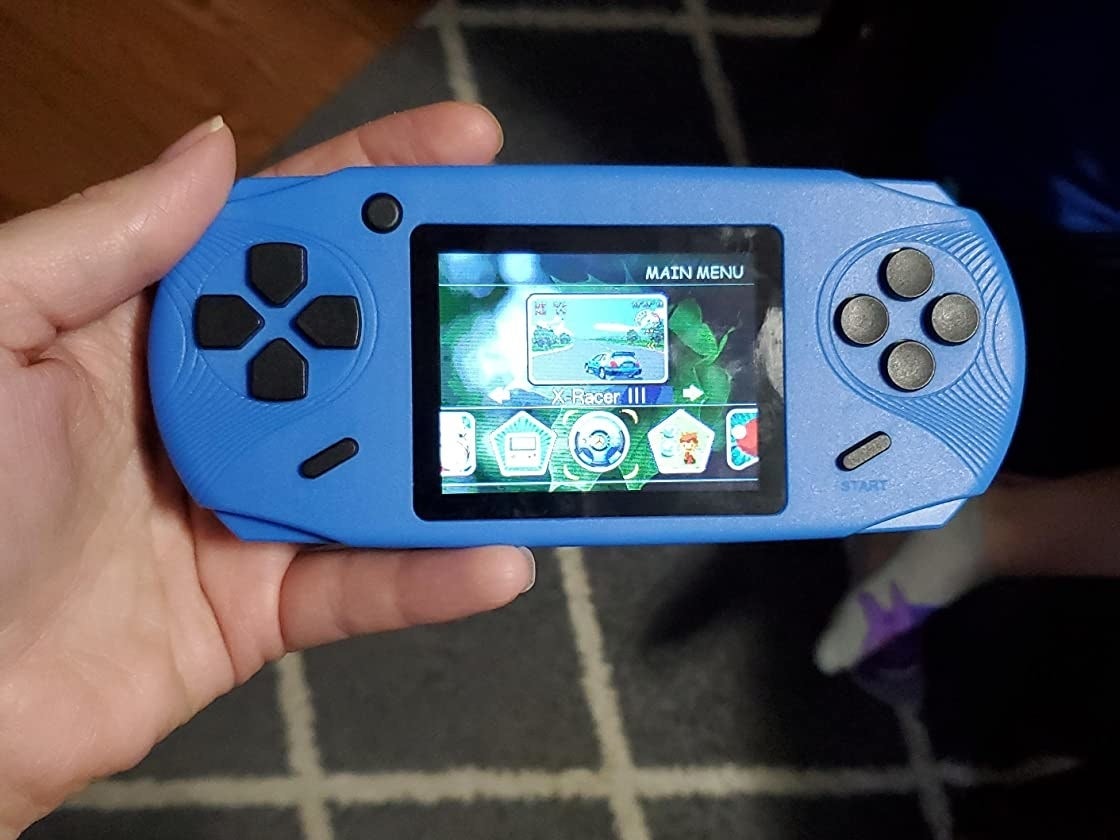 Reviewer&#x27;s photo of hand holding a blue video game device for scale