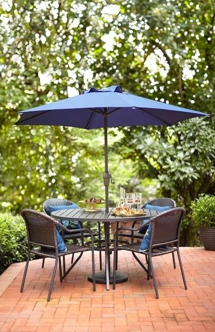the metal dining table with chairs around it and an umbrella