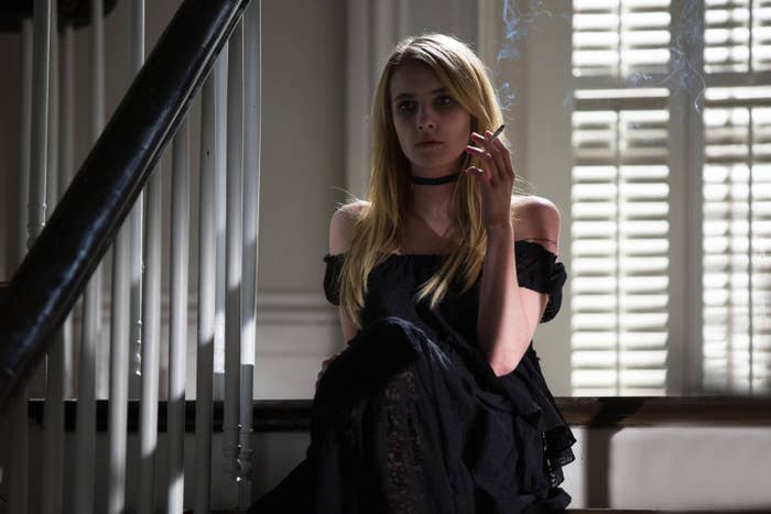 Emma sitting on a set of steps smoking in a scene from American Horror Story