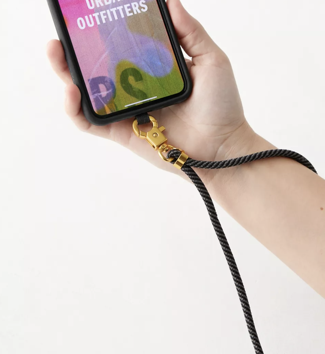 a person holding the phone with the lanyard attached in front of a plain background