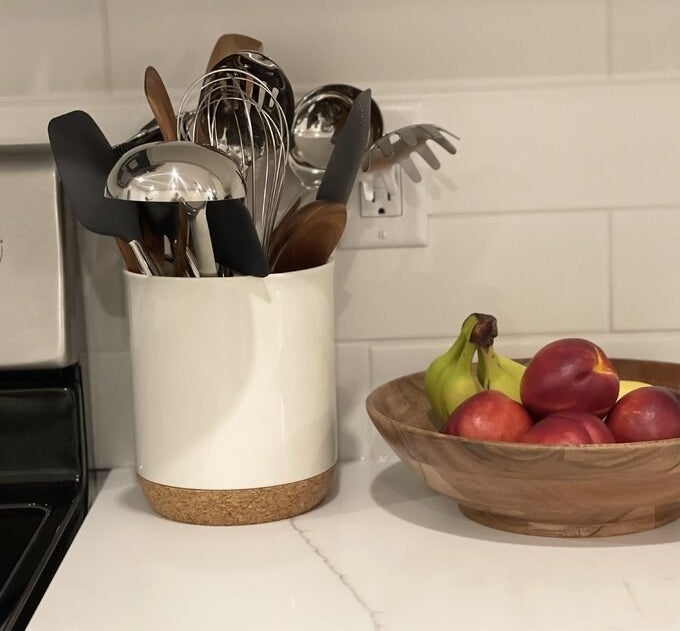 The utensil crock next to a bowl of fruit