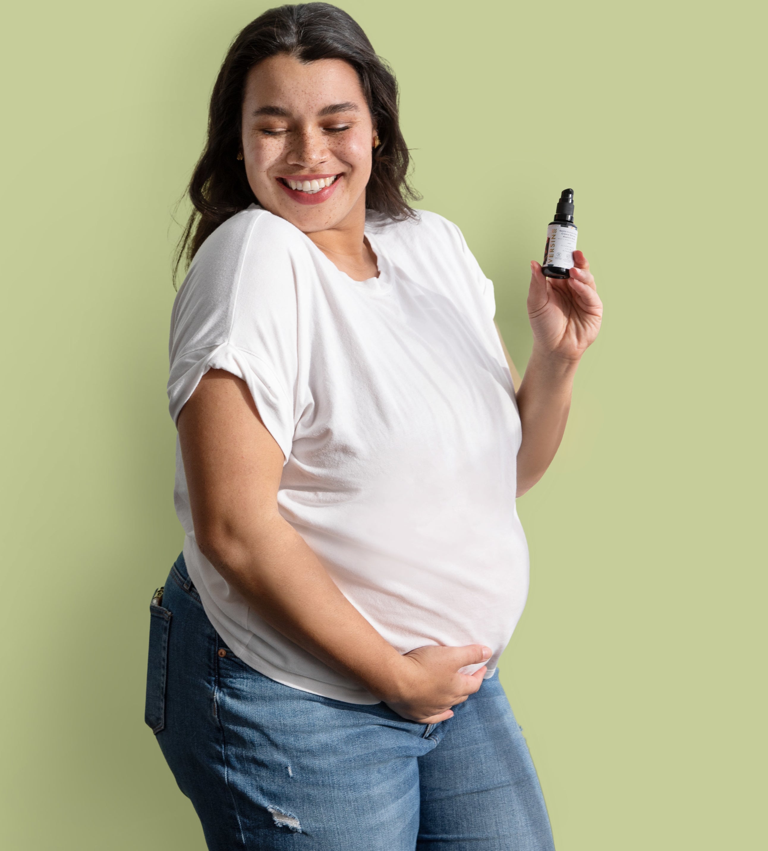 a pregnant person holding a bottle of versine skincare serum