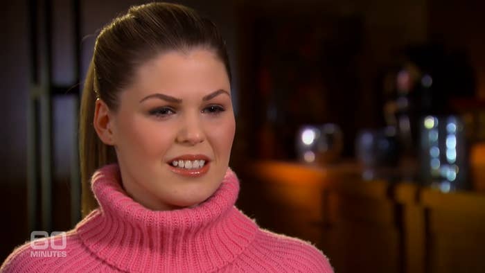 Belle in an interview wearing a pink turtleneck sweater and her hair in a ponytail